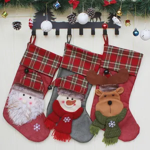 Drei Weihnachtsstrümpfe mit Weihnachtsmann, Schneemann und Rentier an dekorierter Wand
