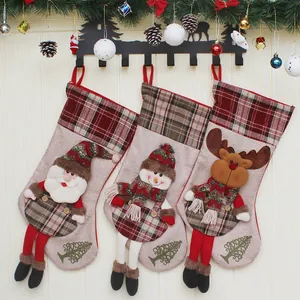 Tre calze di Natale con Babbo Natale, pupazzo di neve e renna appese a una parete di legno