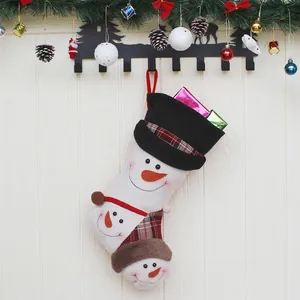 Weihnachtsstrumpf mit Schneemanndesign und Zylinder an Holzwand mit Weihnachtsdekoration