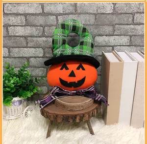 Calabaza de Halloween de peluche con sombrero a cuadros y lazo morado en un taburete