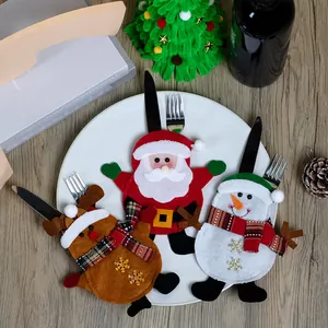 Dettaglio dei portaposate di Babbo Natale e renna su un tavolo festivo in legno