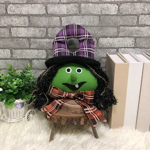 Muñeca de bruja de Halloween con cara verde y sombrero a cuadros morados en soporte madera