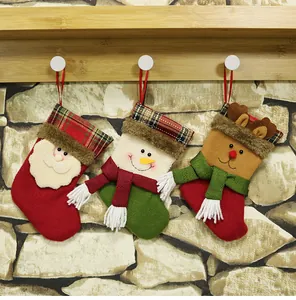 Close-up of three hanging Christmas stockings with Santa, Snowman and Reindeer on stone wall