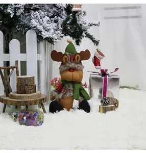 Detail of a plush Christmas reindeer toy with a red nose and plaid hat in festive setting