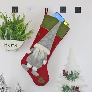Detail eines Weihnachtsstrumpfs mit grauem Wichtel und grünem Herz an festlicher Wand