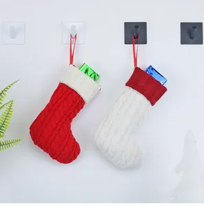 Detail von rot-weißen Strick-Weihnachtssocken an Wandhaken mit kleinen Geschenkboxen