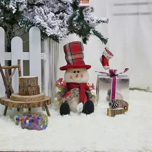 Christmas snowman doll with red plaid hat and scarf in a winter festive scene