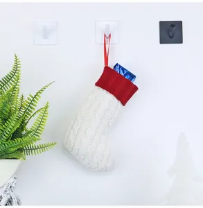 Nahaufnahme einer Zopfstrick-Weihnachtssocke mit rotem Rippbündchen und Geschenk darin