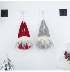 Close-up of red and grey Christmas faceless gnome ornaments with hanging ropes on a wall