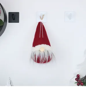 Detail of hanging Christmas gnome with long red hat and soft grey beard on white wall