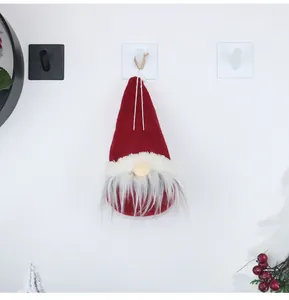 Detail of red Christmas gnome ornament hanging on a wall showing felt texture and soft beard