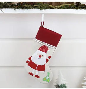 Detail of linen Christmas stocking featuring Santa applique and plush pom-pom trim