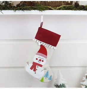 Detail of burlap Christmas stocking featuring a snowman embroidery and white pom-pom trim