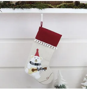 Detail of linen Christmas stocking with plush bear playing guitar and festive decor