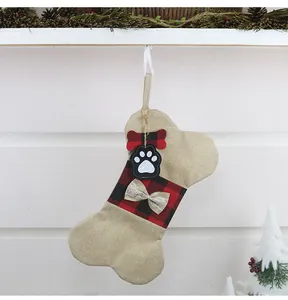 Detail eines knochenförmigen Haustier-Weihnachtsstrumpfs mit rotem Karo auf dem Kamin
