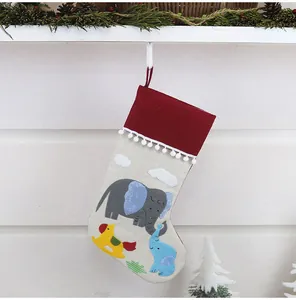 Christmas stocking with elephant embroidery hanging on a fireplace with pine decor