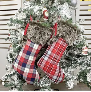 Detail of plaid Christmas stockings with faux fur trim hanging on a snowy festive tree