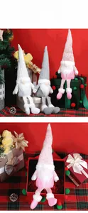 Three plush Christmas gnomes in white, grey, and pink set against a festive red background