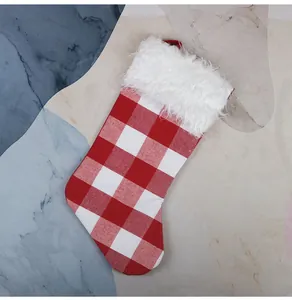 Détail d'une chaussette de Noël à carreaux rouge et blanc avec bordure en peluche