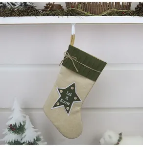 Calza di Natale in lino con stella verde e scritta Let it Snow appesa al camino