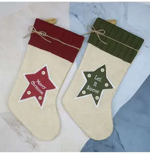 Dettaglio di calze natalizie in juta con ricamo Merry Christmas e decorazioni a stella