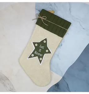 Dettaglio di calza natalizia in iuta con stella verde 'Let it Snow' e fiocco in corda