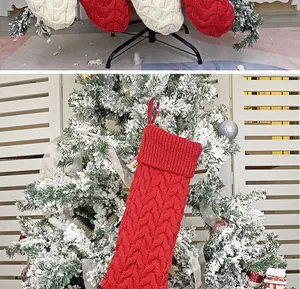 Detail of red and cream cable knit Christmas stockings hanging on a festive snow-dusted tree