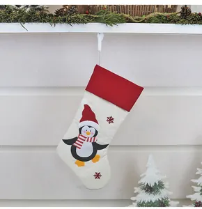 Dettaglio calza di Natale con ricamo a pinguino e motivi di fiocchi di neve rossi
