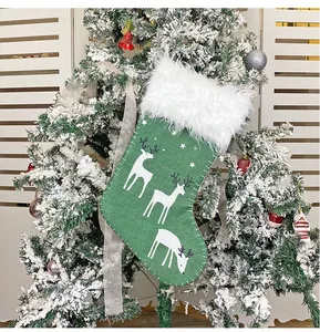 Detail eines grünen Weihnachtsstrumpfs mit Rentier-Print und weißem Pelzbesatz