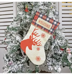 Detail of Christmas stocking with reindeer print and buffalo plaid hanging on a tree