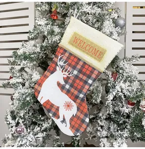 Detail of a red and black buffalo plaid Christmas stocking with a white reindeer and gold sequins