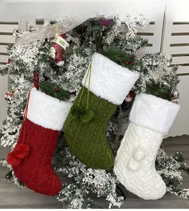 Detailed close-up of cable knit Christmas stockings with plush pom-poms on a tree