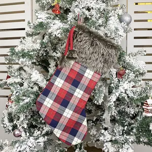 British style plaid Christmas stocking with faux fur trim hanging on snowy tree branch