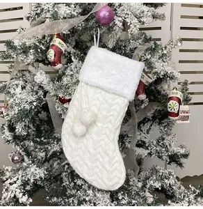 Close-up of a white knitted Christmas stocking with plush faux fur trim and pom-poms