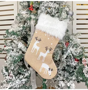 Detail eines Weihnachtsstrumpfs aus Sackleinen mit Plüschrand und Rentierdruck am Baum