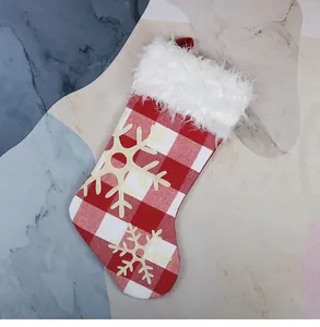 Detail of red buffalo plaid Christmas stocking with white faux fur trim and snowflake patches