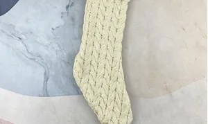 Macro detail of cream knit Christmas stocking with intricate cable weave texture