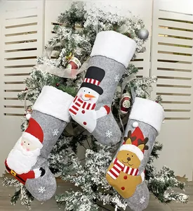 Close-up of three grey Christmas stockings with plush trim on a white holiday tree