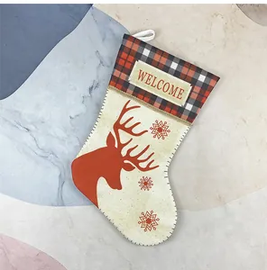 Detail of red buffalo plaid cuff and reindeer print on beige linen Christmas stocking