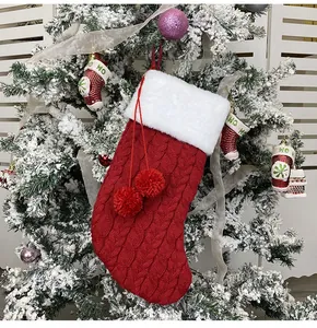 Classic red cable knit Christmas stocking with plush white fur cuff and decorative pompoms