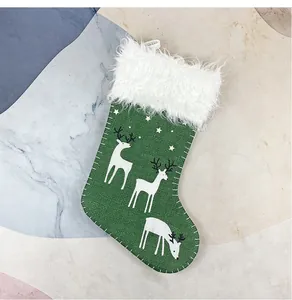 Detail von grünem Weihnachtsstrumpf mit Rentierdruck und flauschigem Kunstfellrand