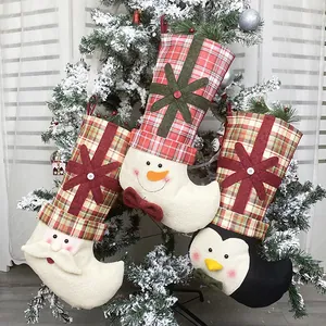 Close-up of Santa, Snowman, and Penguin Christmas stockings hanging on a snowy tree
