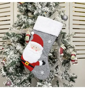 Detail of Christmas stocking with Santa embroidery and faux fur trim on snowy tree