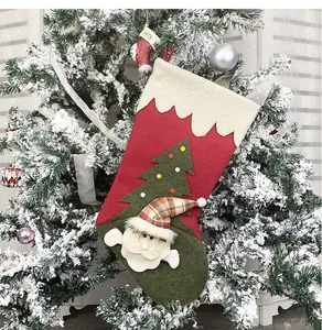 Detail of a large red plush Christmas stocking featuring 3D Santa Claus on a snowy tree
