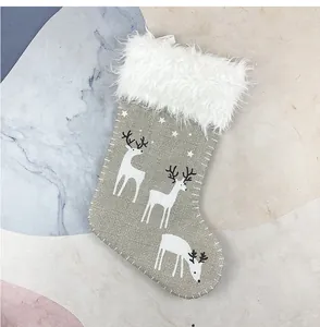 Detailansicht eines grauen Weihnachtsstrumpfs mit Rentierdruck und weißem Kunstfellbesatz.