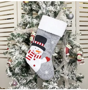 Detailed view of grey felt Christmas stocking with snowman embroidery on a tree