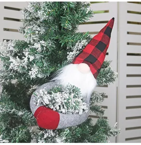 Detail of Christmas gnome curtain buckle with red plaid hat on a snowy pine branch