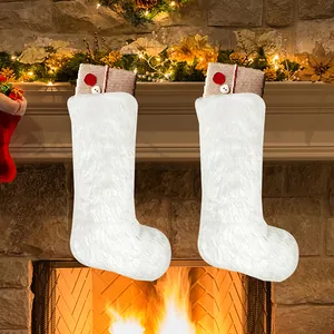 Set of two white faux fur Christmas stockings with button details on a warm fireplace background