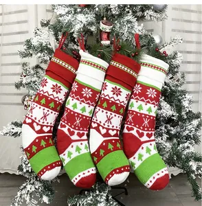 Set di quattro calze di Natale in maglia con motivi a fiocco appese a un albero innevato