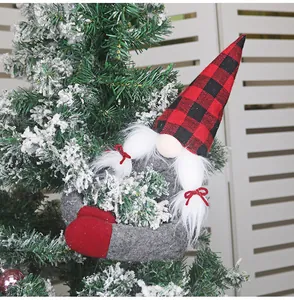 Detail of Christmas gnome plush with red plaid hat hanging on snowy evergreen branches